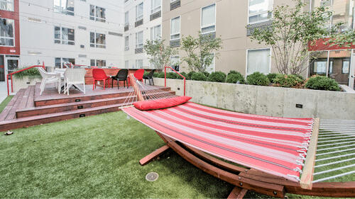 The Urban&#39;s outdoor space with a swimming pool and lawn area surrounded by tall buildings